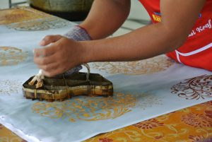 Fabrication d'un tissu batik : Application de la cire à l'aide d'un tampon.